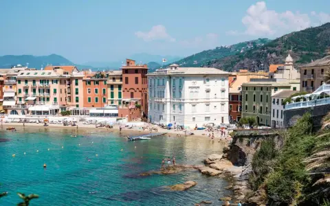 Colorate case affacciate su una spiaggia affollata e un mare turchese, tipico della riviera di Levante.