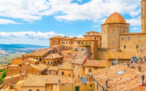 Panoramica di Volterra, con le sue case in pietra e tetti in cotto, che si estende verso le colline toscane, ricordando la bellezza di San Gimignano.