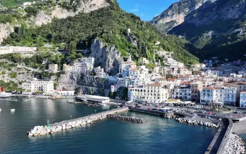 La **conca dei Marini** si apre sul mare blu, con case colorate aggrappate alla scogliera verdeggiante.