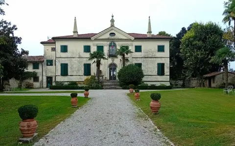 Villa storica con viale di ghiaia e vasi decorativi. Un luogo incantevole per scoprire cosa vedere a Clauiano.