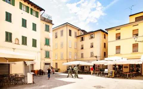 Piazza con edifici storici e tavolini all'aperto, ideale per scoprire cosa vedere a Pistoia in un giorno.