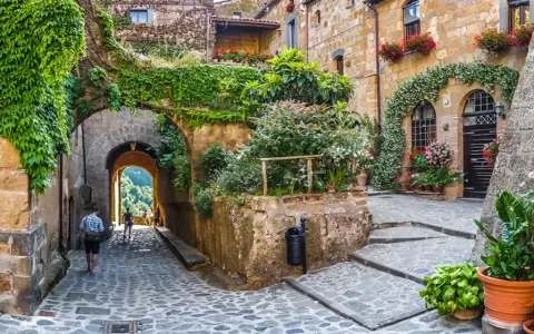 Un vicolo fiorito in uno dei 10 borghi più belli d'Italia, con archi coperti di edera e scorci panoramici.