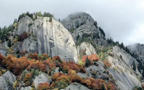 Val di Mello: maestose rocce grigie e boschi autunnali dai colori caldi, un paesaggio mozzafiato da scoprire.