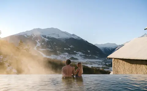 Coppia in una piscina termale con vista sulle montagne innevate. Un'oasi di relax, perfetta per chi cerca terme vicino Milano.