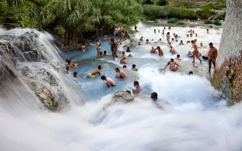 Cascate naturali con persone che si bagnano, un luogo incantevole dove si trovano le terme di Saturnia.