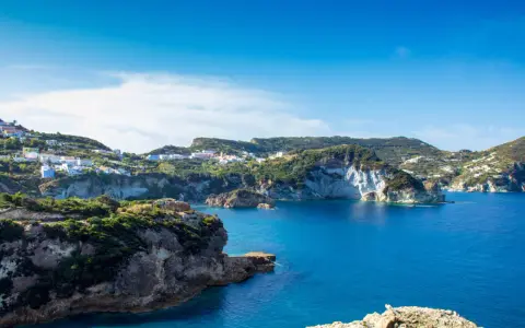 Panoramica della **cala dell'acqua a Ponza**, con case colorate aggrappate alla collina e un mare blu intenso.