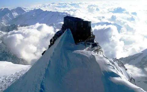 Il rifugio più alto d'Italia, incastonato su una vetta innevata, domina un mare di nuvole.