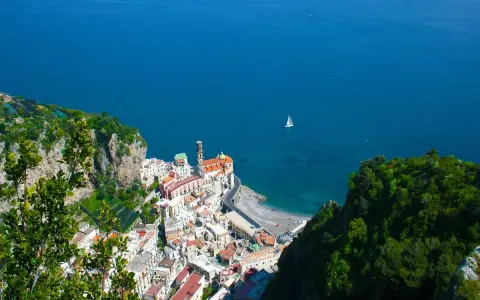 Vista dall'alto di Amalfi, con il mare blu e una barca a vela. La distanza tra Ravello e Amalfi è breve, ma il panorama è mozzafiato.