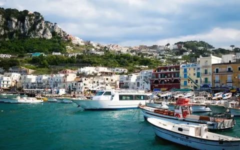 Barche nel porto di Capri, con la città arroccata sulla collina. Un ottimo punto di partenza per capire come raggiungere Capri da Napoli.