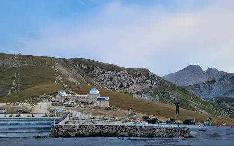 Osservatorio astronomico sul Gran Sasso, con montagne imponenti sullo sfondo. Un luogo ideale per gli alpinisti che amano la natura e il cielo stellato.