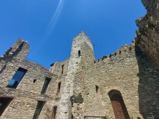 Rovine di un castello nel centro storico di Passignano sul Trasimeno, con mura in pietra e cielo azzurro.