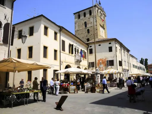 Mercato in piazza a Portobuffolè cosa vedere: bancarelle di antiquariato e la torre civica sullo sfondo.