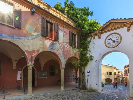 Un angolo suggestivo tra i borghi da visitare in Romagna. Archi affrescati, un portale con orologio e un vicolo acciottolato invitano alla scoperta.