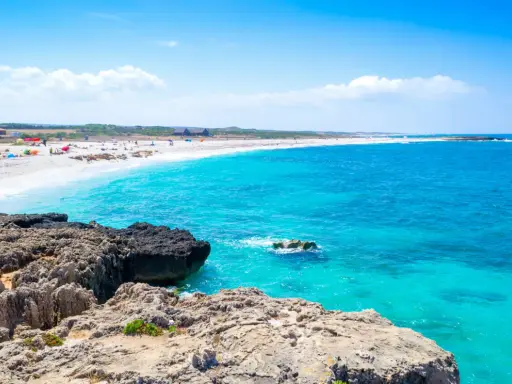 Scogli vulcanici e sabbia bianca su una spiaggia pop corn in Sardegna, con acque turchesi cristalline.