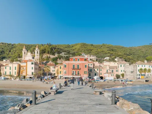 Laigueglia centro storico: case colorate affacciate sulla spiaggia, con una chiesa a due campanili e il mare azzurro.