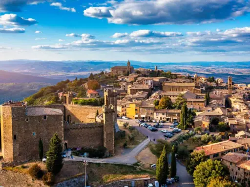 Un borgo medievale arroccato su una collina, tra i più belli d'Italia, con un castello imponente e case in pietra sotto un cielo azzurro.