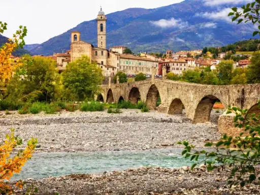 Ponte Gobbo a Bobbio, borgo dei borghi, con il fiume e le montagne sullo sfondo.
