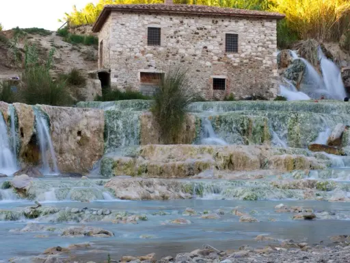Cascate termali naturali con un antico mulino in pietra, un'oasi di benessere nel cuore delle terme centro Italia.