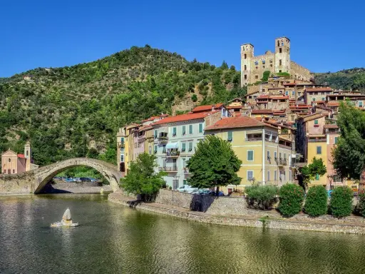 Borghi entroterra ligure levante: un ponte antico attraversa un fiume, case colorate si affacciano sull'acqua, un castello domina la collina verde.