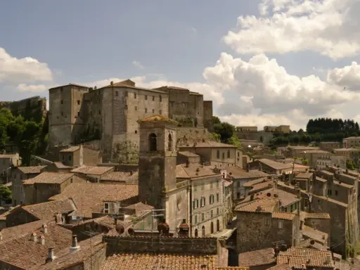 Panoramica di antichi borghi vicino Follonica, con un imponente castello in cima alla collina e un campanile che svetta tra i tetti rossi.