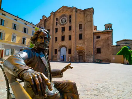 Statua di bronzo in piazza, con edifici storici sullo sfondo. Un assaggio delle città più belle Emilia Romagna.
