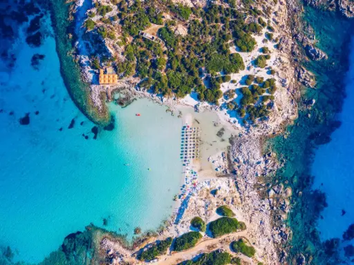Spiaggia paradisiaca con acque cristalline, perfetta per itinerari Sardegna nord 7 giorni. Ombrelloni e lettini invitano al relax.