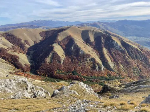 Autunno nel Val di Norcia, con montagne dolci e boschi dai colori caldi che scendono verso la valle.