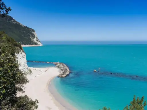 Spiagge piu belle d'Italia: una caletta di sabbia bianca incastonata tra scogliere a picco e un mare turchese cristallino.