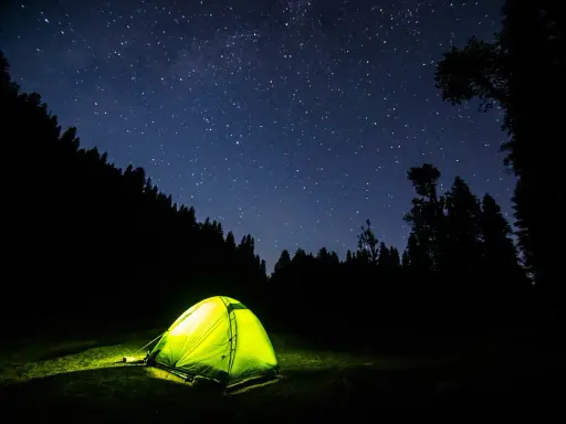 Tenda illuminata nella notte stellata, un invito a dormire in tenda immersi nella natura.