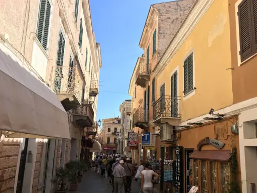 Passeggiata in un vicolo colorato, ideale per visitare La Maddalena in auto, con edifici storici e negozietti.