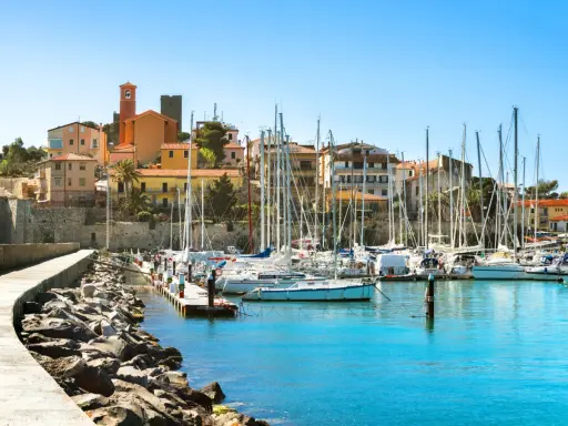 Porto turistico con barche a vela ormeggiate e case colorate che si affacciano sul mare, nel cuore del talamone centro storico.