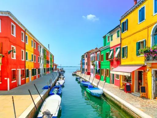 Colorate case affacciate su un canale con barche ormeggiate, un'incantevole scena di **Murano e Burano**.