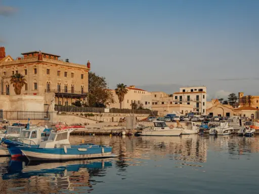 Porto di Favignana con barche ormeggiate e edifici storici. Per sapere come arrivare a Favignana, guarda questo porto!