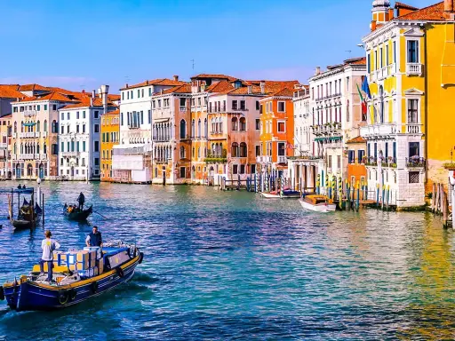 Gondole e vaporetti sul Canal Grande, un assaggio di cosa vedere a Venezia in due giorni. Palazzi colorati e acqua scintillante.
