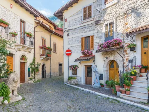 Antica via acciottolata tra **borghi Abruzzo sul mare**, con case in pietra e fiori colorati sui balconi.