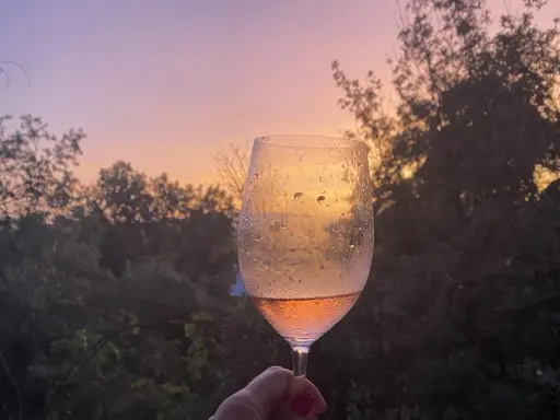 Un calice di vino rosato riflette il tramonto sulle dolci colline del Chianti.