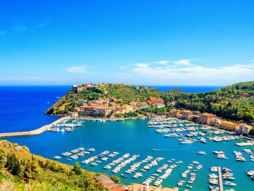 Porto Ercole, con le sue splendide spiagge e il porto pieno di barche, incanta sotto un cielo azzurro.