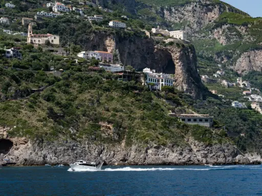 Un traghetto da Amalfi a Positano sfreccia nel mare blu, con case bianche aggrappate alle scogliere verdi.