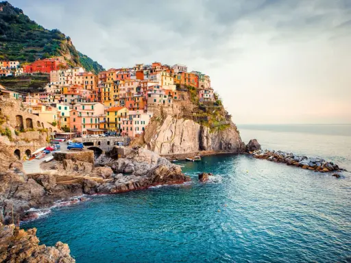 Manarola, uno dei borghi italiani da visitare, si aggrappa alla scogliera con le sue case colorate che si tuffano nel mare blu.