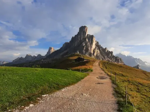 Sentiero per escursioni al Passo Giau, con imponenti vette rocciose e un rifugio alpino.