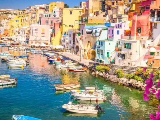Porto di Corricella a Procida, un gioiello colorato. Ecco cosa vedere a Procida in un giorno: case pastello, barche nel blu intenso e bouganville in fiore.