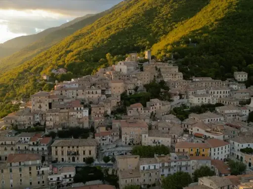 Borgo San Donato, un incantevole paese arroccato su un colle, immerso nel verde di una montagna illuminata dal sole al tramonto.