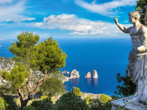 Statua antica guarda il mare blu intenso e i Faraglioni, icona dell'isola vicino Capri.