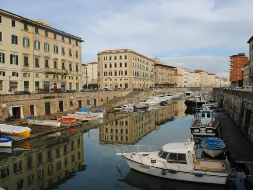 Canali e palazzi storici a Livorno, perfetti per gite di un giorno. Barche ormeggiate riflettono l'architettura.