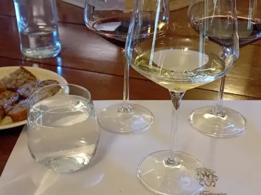 Calici di vino bianco e rosso, pane tostato e acqua per una degustazione vini Bolgheri.