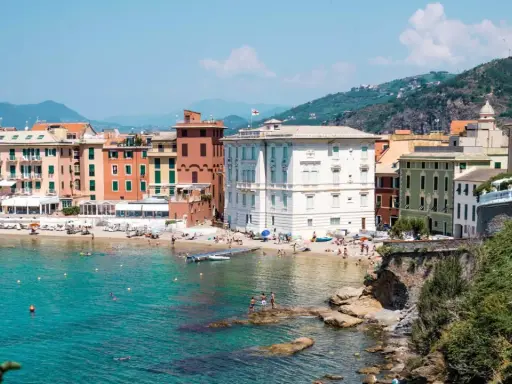 Colorate case affacciate su una spiaggia affollata e un mare turchese, tipico della riviera di Levante.