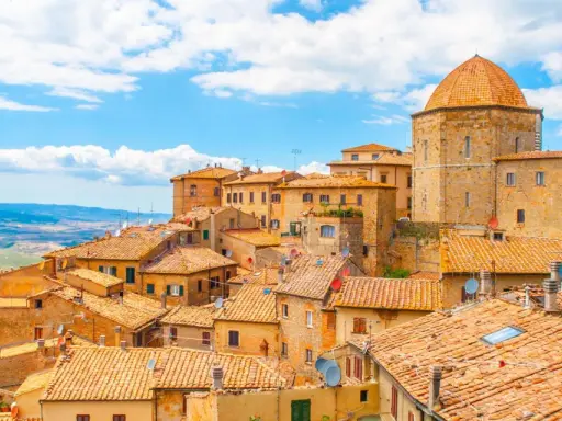 Panoramica di Volterra, con le sue case in pietra e tetti in cotto, che si estende verso le colline toscane, ricordando la bellezza di San Gimignano.