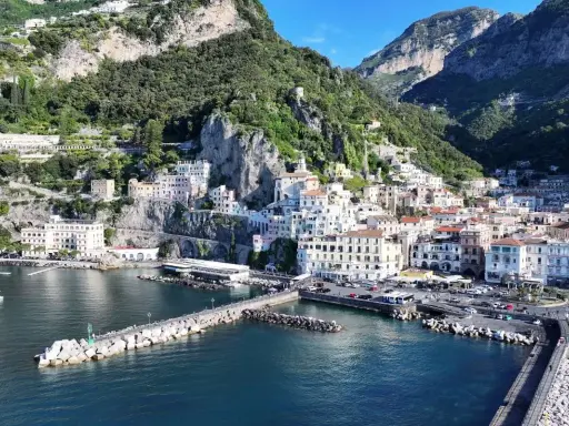 La **conca dei Marini** si apre sul mare blu, con case colorate aggrappate alla scogliera verdeggiante.