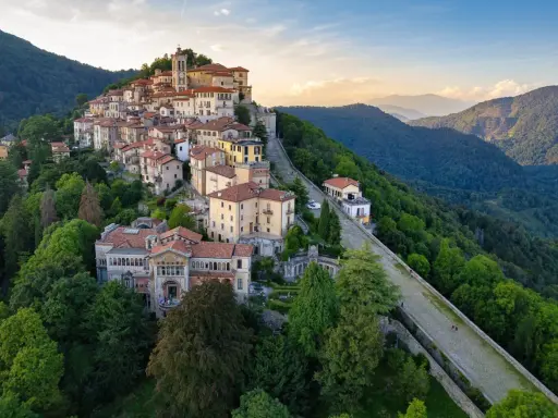 Borgo pittoresco su un colle, ideale per scoprire cose da fare a Varese. Case colorate, un campanile e sentieri panoramici tra il verde.
