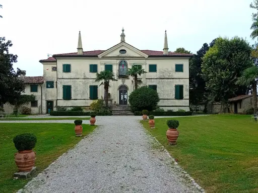 Villa storica con viale di ghiaia e vasi decorativi. Un luogo incantevole per scoprire cosa vedere a Clauiano.